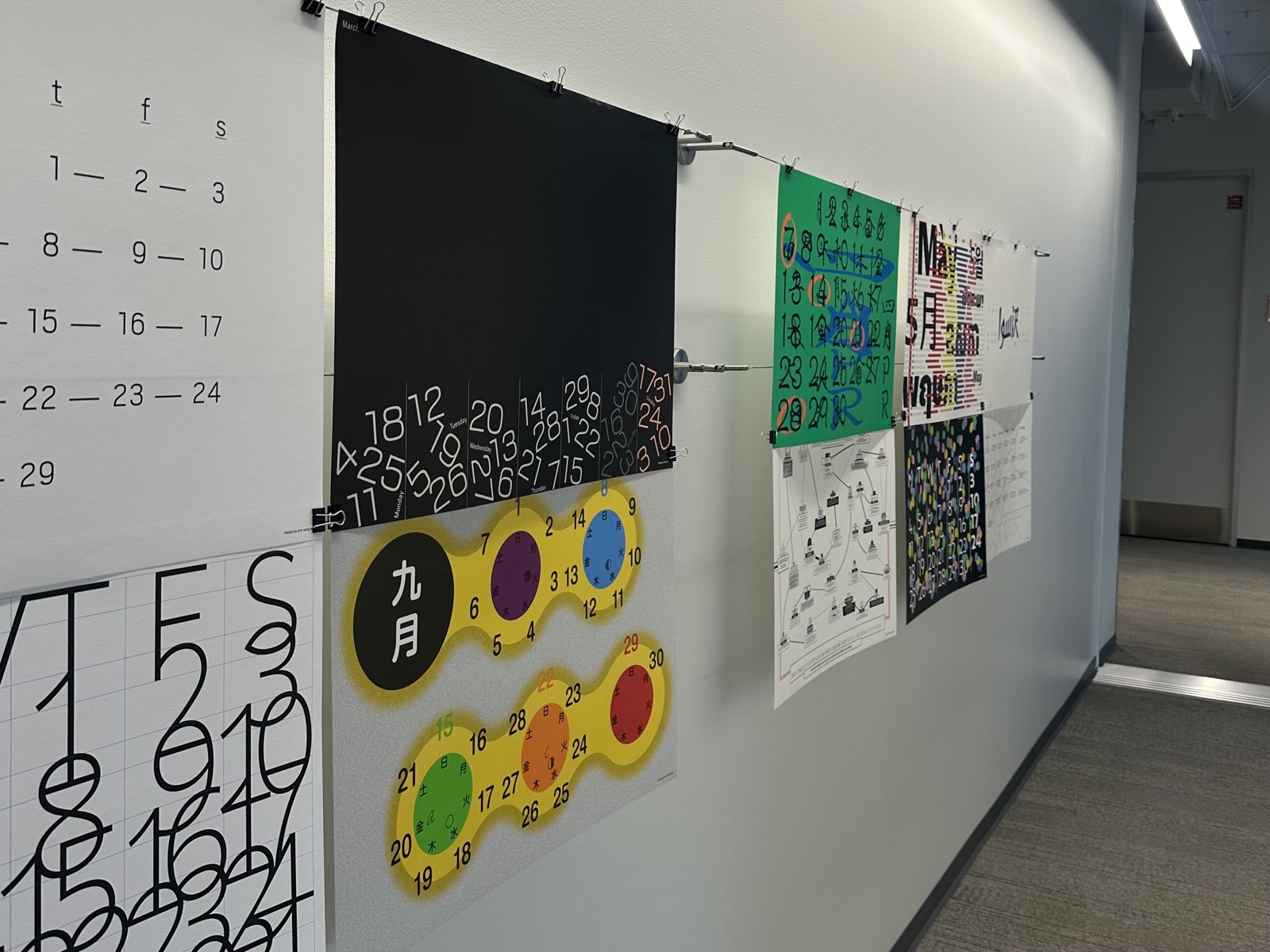 Morisawa calendar posters clipped to a wire along an office hallway